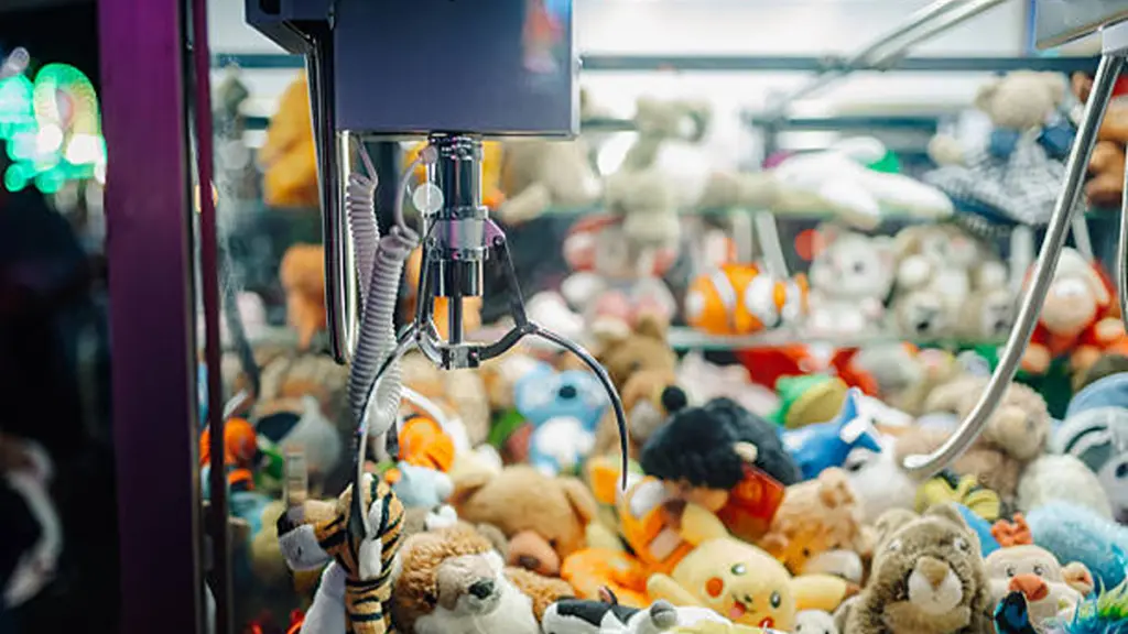 Claw crane picking up plush toys in arcade game machine