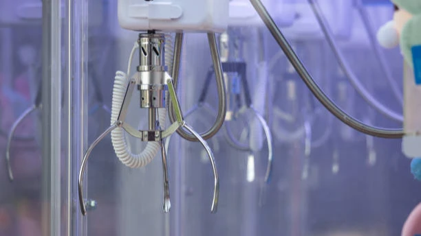 Close-up view of a white claw machine handle with a coiled cord and metal claw mechanism inside the glass case.